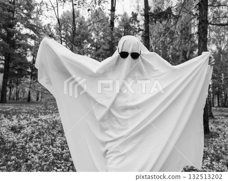 Woman in a ghost costume against the backdrop of an autumn forest. Halloween costume. Black and white photo.  132513202