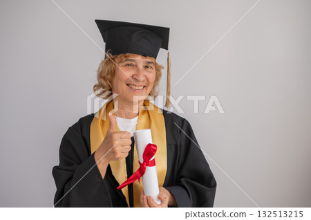 Happy senior woman in graduation gown holding diploma on white background. Happy senior woman in graduation gown holding diploma on white background. 132513215