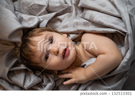 Top view of cute caucasian toddler lying in bed.  132513301