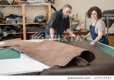 A man and a woman work as tanners in a workshop. A man and a woman work as tanners in a workshop. 132513332