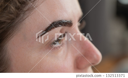 Caucasian woman getting eyebrow tinting procedure. Caucasian woman getting eyebrow tinting procedure. 132513371