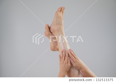 Woman applying moisturizer to her legs. White background. Woman applying moisturizer to her legs. White background. 132513375