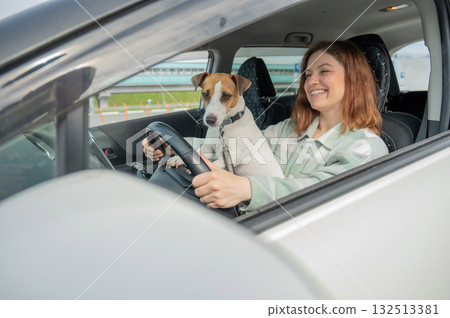 Caucasian woman traveling by car with her dog.  132513381
