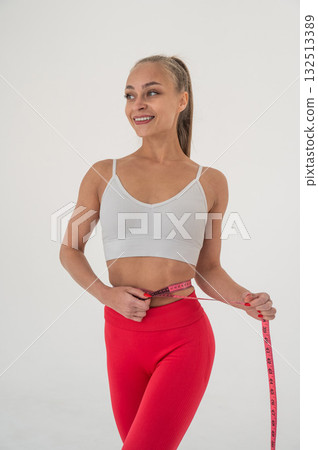 Young woman measuring her waist on white background. Young woman measuring her waist on white background. 132513389