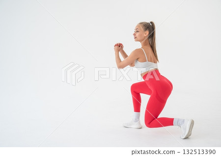 Young woman doing lunges on white cyclorama background. Vertical video. Young woman doing lunges on white cyclorama background. Vertical video. 132513390