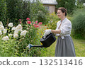 Young Caucasian woman watering flowers in the garden.  132513416