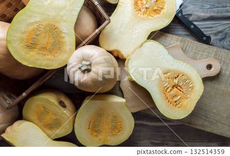 Ripe pumpkins on a wooden background.Whole and cut fruits of a yellow gourd.Top view.Seasonal vegetable autumn recipes Ripe pumpkins on a wooden background.Whole and cut fruits of a yellow gourd.Top view.Seasonal vegetable autumn recipes 132514359