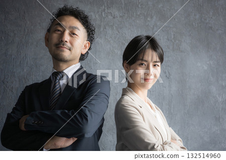 Smiling man and woman in suits with their arms crossed. Image of executive work such as consulting or legal profession. 132514960