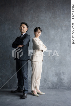 Smiling man and woman in suits with arms crossed, full body. Image of executive work such as consulting or professional work. 132514961