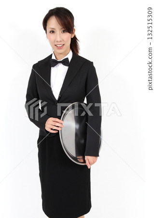 A woman standing in front of a white background holding a round tray 132515309