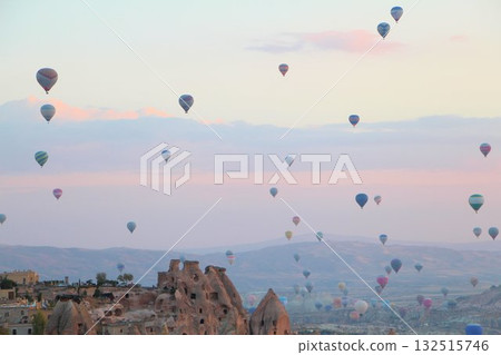 A mystical landscape of many hot air balloons flying over Uchisar, a tourist attraction in Türkiye 132515746