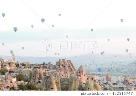 A mystical landscape of many hot air balloons flying over Uchisar, a tourist attraction in Türkiye 132515747