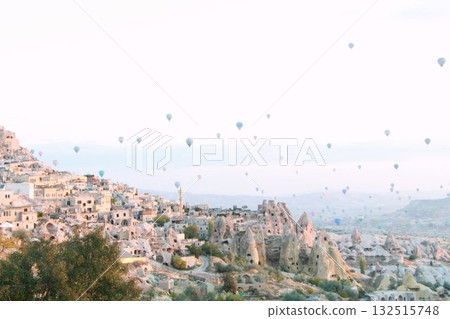 A mystical landscape of many hot air balloons flying over Uchisar, a tourist attraction in Türkiye 132515748