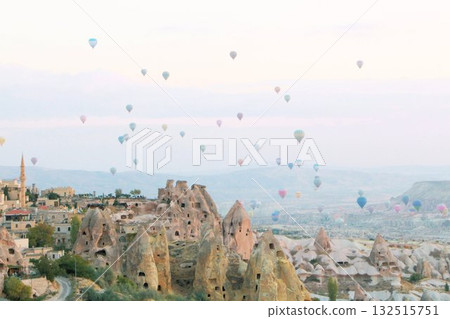 A mystical landscape of many hot air balloons flying over Uchisar, a tourist attraction in Türkiye 132515751