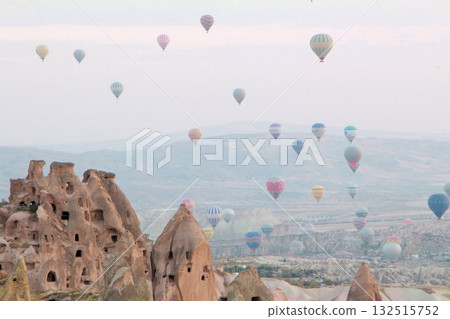 A mystical landscape of many hot air balloons flying over Uchisar, a tourist attraction in Türkiye 132515752