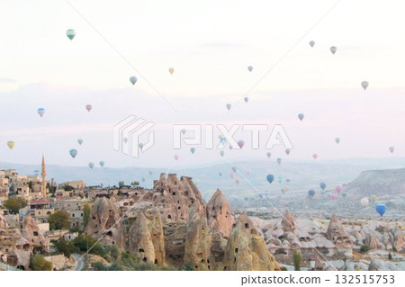 A mystical landscape of many hot air balloons flying over Uchisar, a tourist attraction in Türkiye 132515753