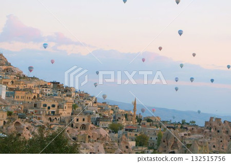 A mystical landscape of many hot air balloons flying over Uchisar, a tourist attraction in Türkiye 132515756