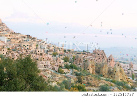 A mystical landscape of many hot air balloons flying over Uchisar, a tourist attraction in Türkiye A mystical landscape of many hot air balloons flying over Uchisar, a tourist attraction in Türkiye 132515757