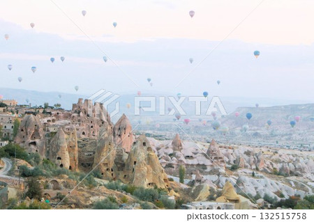 A mystical landscape of many hot air balloons flying over Uchisar, a tourist attraction in Türkiye 132515758