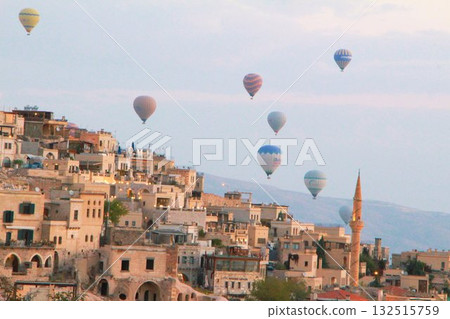 A mystical landscape of many hot air balloons flying over Uchisar, a tourist attraction in Türkiye 132515759