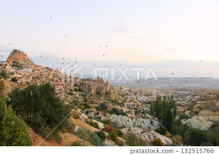 A mystical landscape of many hot air balloons flying over Uchisar, a tourist attraction in Türkiye 132515760