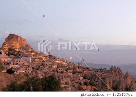 A mystical landscape of many hot air balloons flying over Uchisar, a tourist attraction in Türkiye 132515762