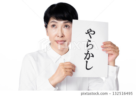 A senior woman wearing a white shirt holding a piece of paper with the word "yakashi" written on it and sticking out her tongue A senior woman wearing a white shirt holding a piece of paper with the word "yakashi" written on it and sticking out her tongue 132516495
