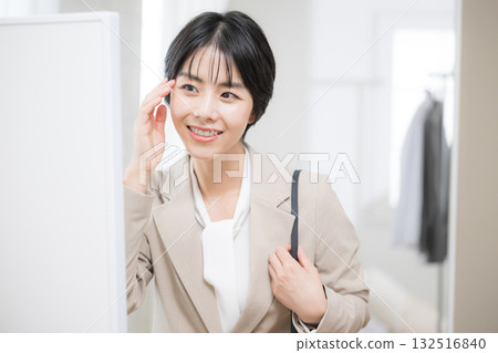 A woman in a suit checking her appearance before going to work. I'm off. 132516840