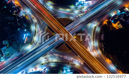 Fast traffic blurs on the city highway at night, forming bright light trails across the dark urban cityscape Fast traffic blurs on the city highway at night, forming bright light trails across the dark urban cityscape 132516977