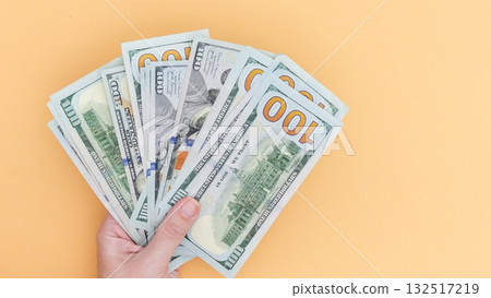 Hand Holding Stack of Hundred Dollar Bills on Yellow Background. Financial Prosperity Concept. Hand Holding Stack of Hundred Dollar Bills on Yellow Background. Financial Prosperity Concept. 132517219
