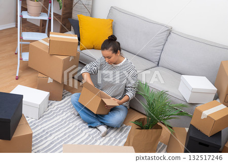 Moving Day woman surrounded by boxes, unbox her home decoration, relocation in new life. Moving Day woman surrounded by boxes, unbox her home decoration, relocation in new life. 132517246