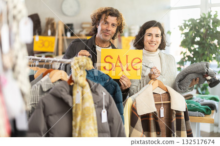 Happy couple, woman and man holding sign saying Sale for winter season standing in interior of clothing boutique 132517674