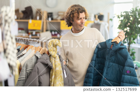 Man choosing a down jacket in a clothing store Man choosing a down jacket in a clothing store 132517699