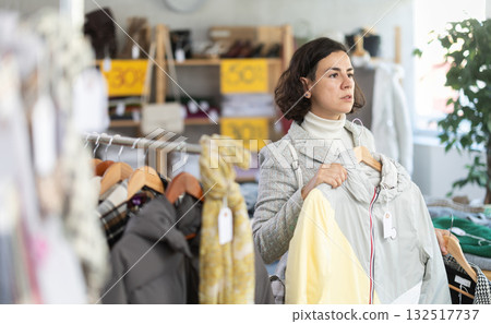European female customer examine and choose new coat or jacket for cold season in modern store 132517737