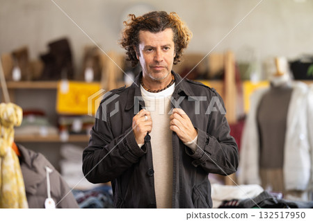 Man try on brawn cloak in front of mirror in clothes store Man try on brawn cloak in front of mirror in clothes store 132517950