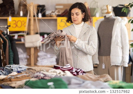 Woman at the counter in the store choosing pants Woman at the counter in the store choosing pants 132517982