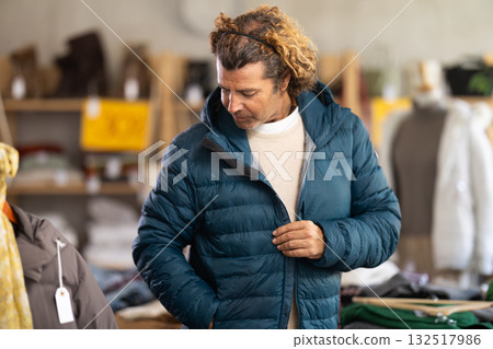 Man trying on a down jacket in a store 132517986