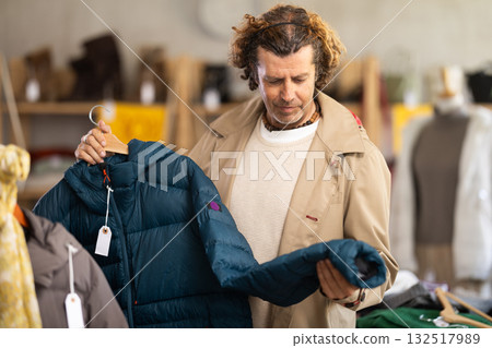 Man choosing a down jacket in a clothing store Man choosing a down jacket in a clothing store 132517989