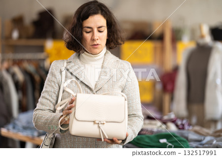 Latin American woman search and choose leather bag in shop Latin American woman search and choose leather bag in shop 132517991