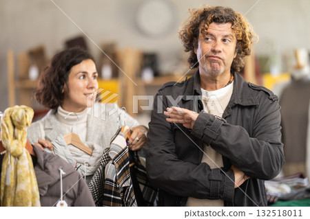 Annoyed man standing next to woman in store Annoyed man standing next to woman in store 132518011