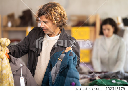 Man search and choose down jacket in store Man search and choose down jacket in store 132518179