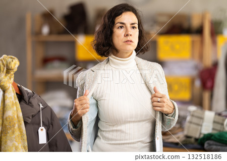 woman tries on a blazer in a clothing store woman tries on a blazer in a clothing store 132518186