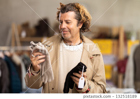 Focused male client choosing warm gloves for winter season in clothing store Focused male client choosing warm gloves for winter season in clothing store 132518189