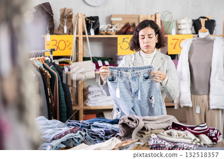 Latin American woman search and choose jeans trousers in shop 132518357