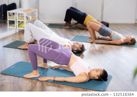 Asian woman oing glute bridge during group Pilates session 132518384