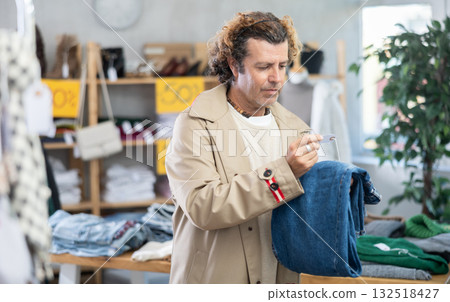 Man search and choose jeans trousers in store Man search and choose jeans trousers in store 132518427