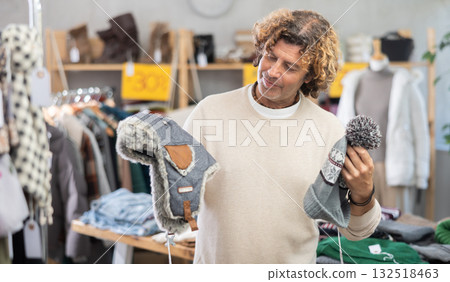 Curly man choosing a hat in the store Curly man choosing a hat in the store 132518463