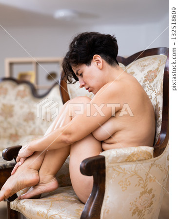 Sensual nude Latin female hugging knees while sitting curled up on chair at home Sensual nude Latin female hugging knees while sitting curled up on chair at home 132518609