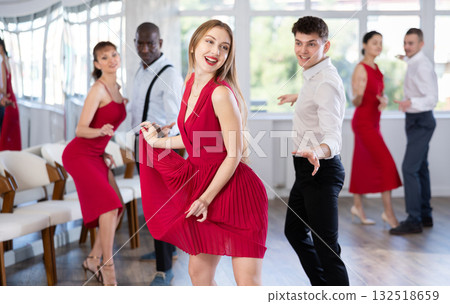 Group of young active people practicing vogue dancing movements while training twist or charleston in dance hall 132518659
