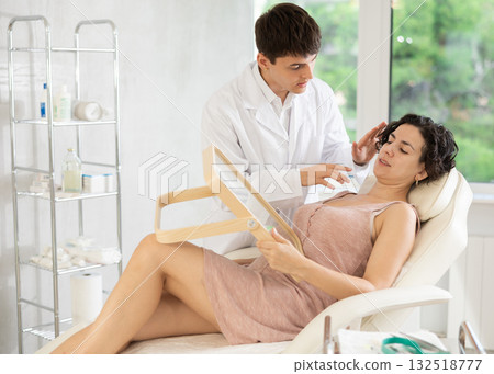 Middle-aged woman having consultation about face aesthetic while looking in the mirror Middle-aged woman having consultation about face aesthetic while looking in the mirror 132518777
